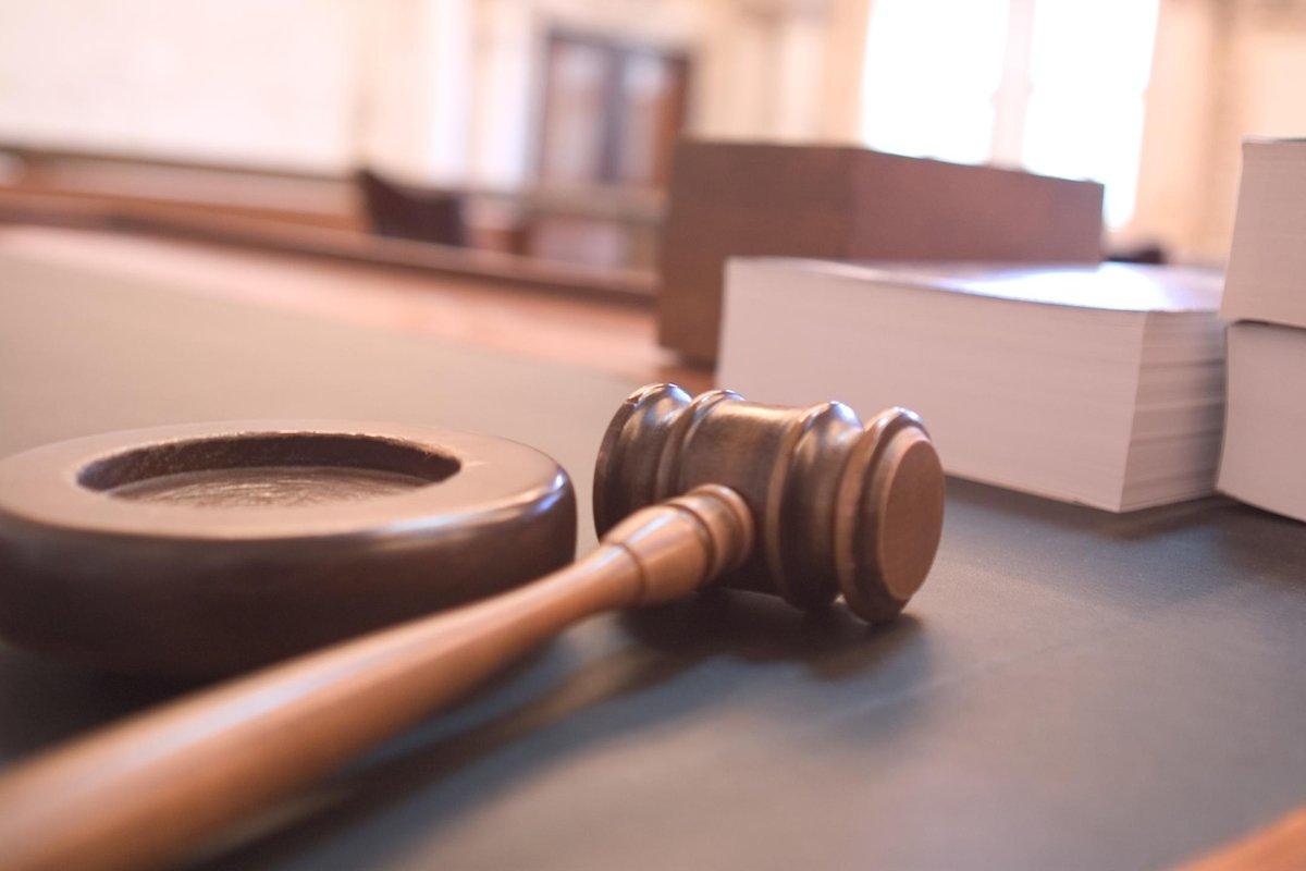 A judge's gavel resting on a courtroom table.